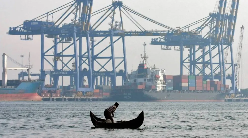 صياد في مركب صغير أمام سفينة حاويات راسية بميناء في مدينة كوتشي جنوب الهند (رويترز)