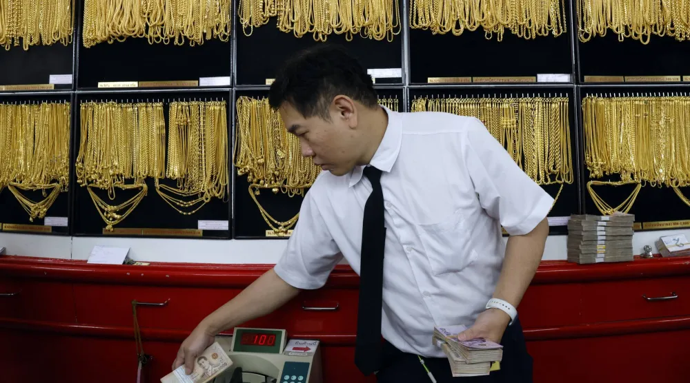 صائغ ذهب يعدّ الأوراق النقدية خلال عملية تداول الذهب في متجر للذهب في بانكوك  (إ.ب.أ)
