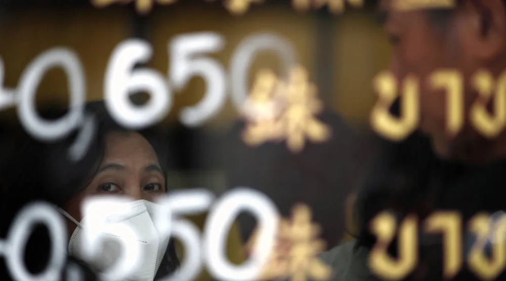 ينتظر أحد الزبائن دوره لتداول الذهب خلف نافذة زجاجية تعرض أسعار الذهب في متجر  للذهب في بانكوك (إ.ب.أ)