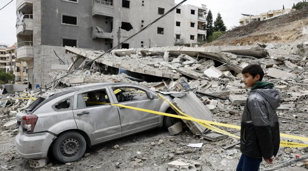 فتى أمام مبنى دمرته غارة إسرائيلية على بلدة قناريت جنوب لبنان الأربعاء (إ.ب.أ)