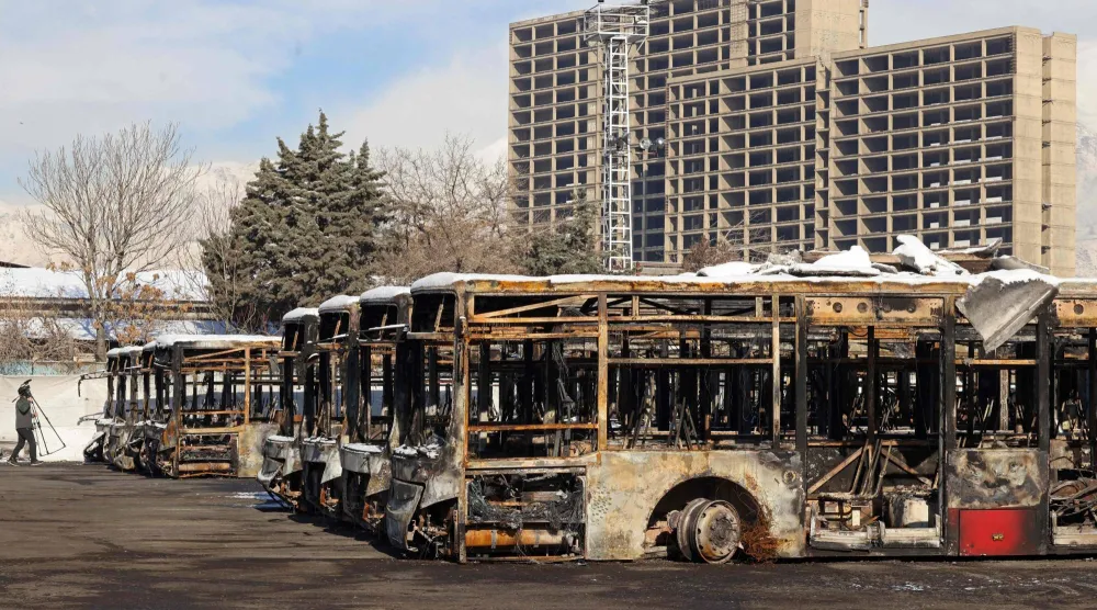 This photograph taken during a tour for foreign media shows a media representative walking past the parked buses that were burned at a depot during recent public protests, in Tehran on January 21, 2026. (AFP)