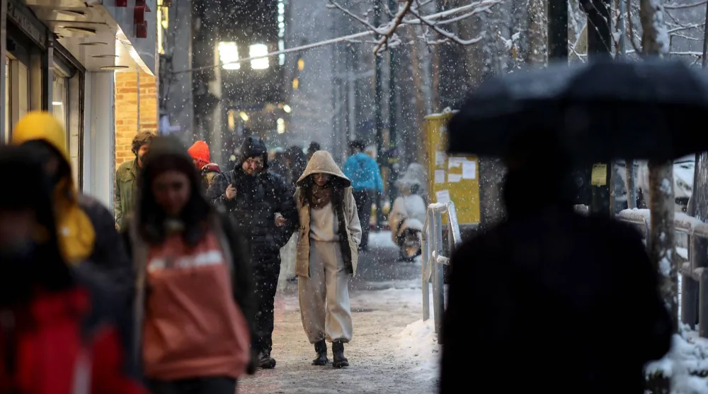 إيرانيون يمشون في أحد شوارع طهران مع تساقط الثلج (رويترز)