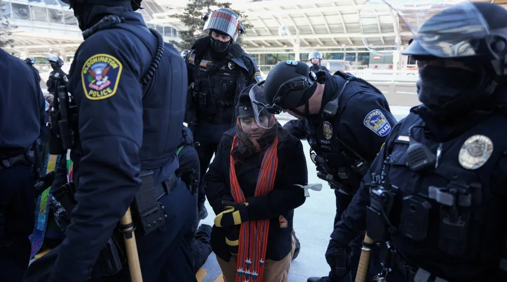 ضباط شرطة أميركيون يعتقلون رجلاً خلال مسيرة احتجاجية ضد قوانين الهجرة في مدينة مينيابوليس بولاية مينيسوتا (رويترز)