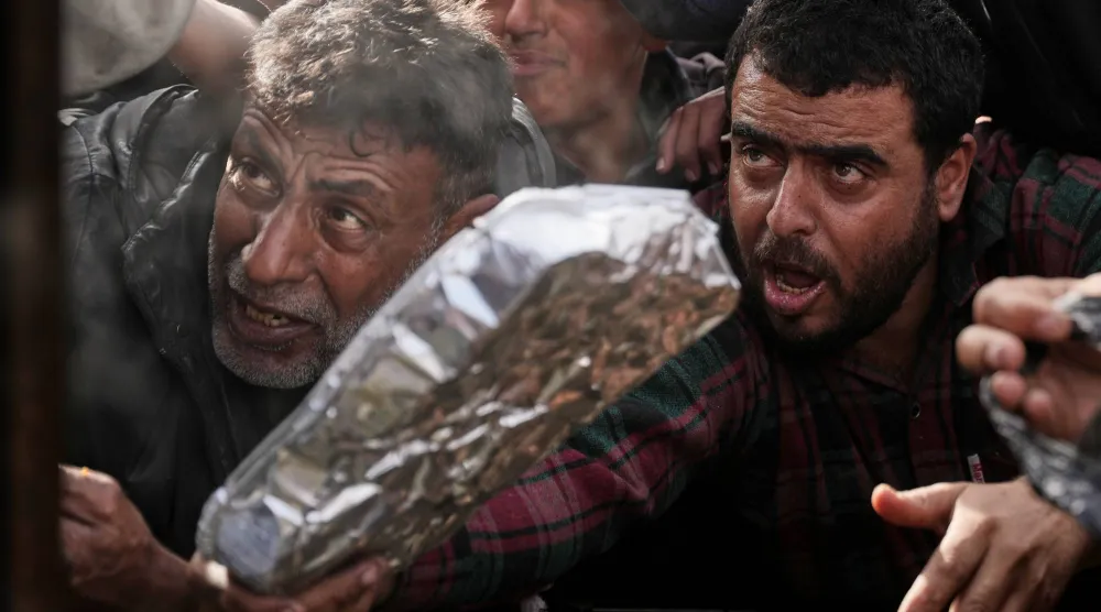 فلسطينيون ينتظرون الحصول على طعام في خان يونس جنوب قطاع غزة (أ.ب)