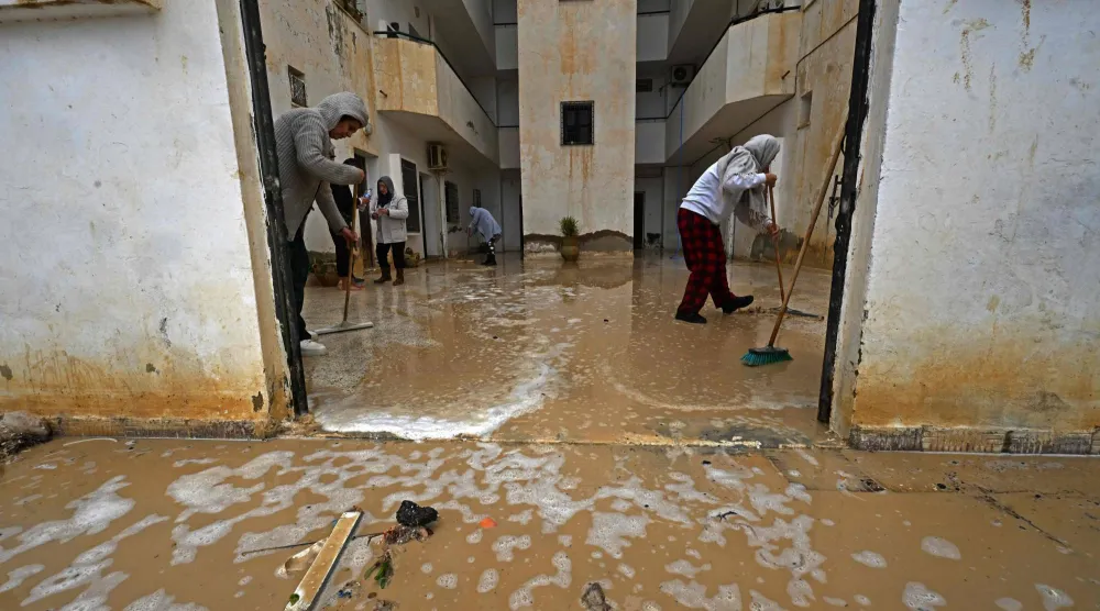 تونسي من منطقة أريانة ينظف آثار السيول (أ.ف.ب)