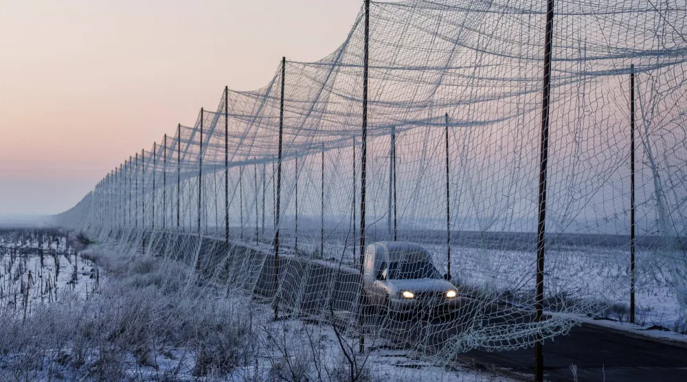 سيارة تتحرك على طريق مغطى بشباك مضادة للمسيرات في منطقة خاركيف بأوكرانيا (رويترز)