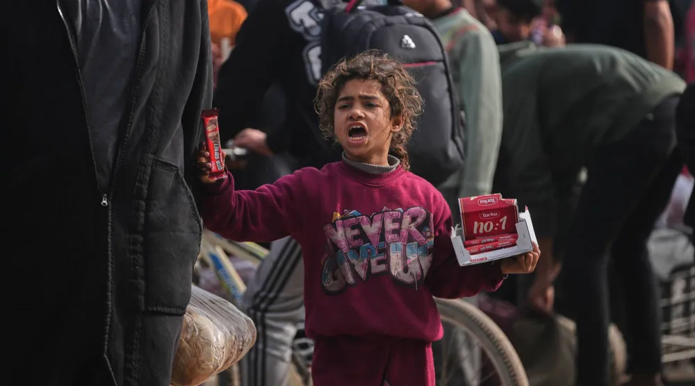 طفلة فلسطينية تبيع ألواح شوكولاتة في سوق بخان يونس جنوب قطاع غزة الجمعة (أ.ب)