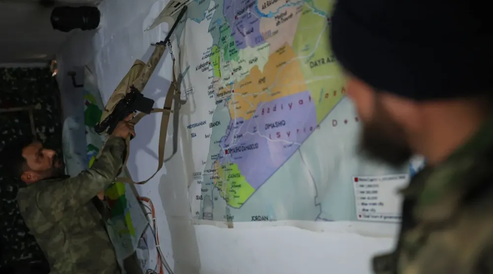 Dün Rakka kırsalındaki Ayn İsa'dan çekildikten sonra SDG tarafından boşaltılan bir tünelde Suriye haritasının önünde duran Suriye hükümeti güçlerinin iki üyesi (AP)