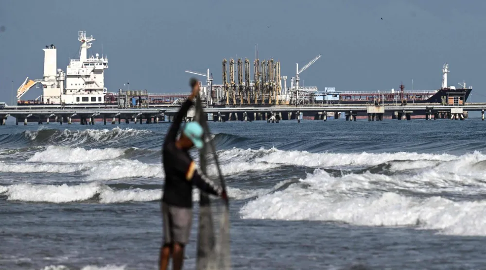 صياد على شاطئ البحر بينما ترسو ناقلة نفط في رصيف مصفاة إل باليتو في بويرتو كابيلو بولاية كارابوبو في فنزويلا (أ.ف.ب)