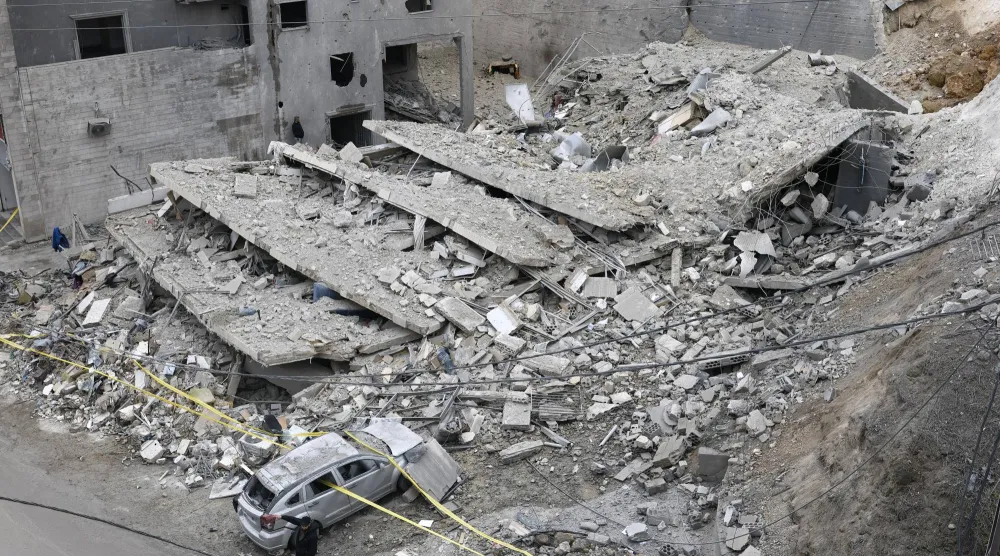 رجل يسير بجوار مبنى مدمر عقب غارة جوية إسرائيلية على قرية قناريت... جنوب لبنان في 22 يناير 2026 (إ.ب.أ)