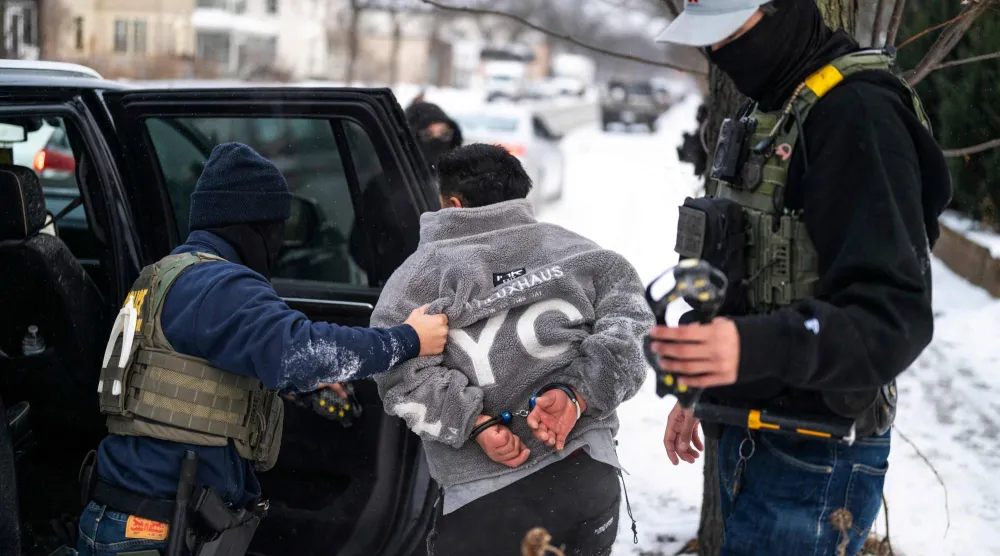 رجل يحتجزه عنصر من إدارة الهجرة الأميركية بولاية مينيسوتا (أ.ف.ب)