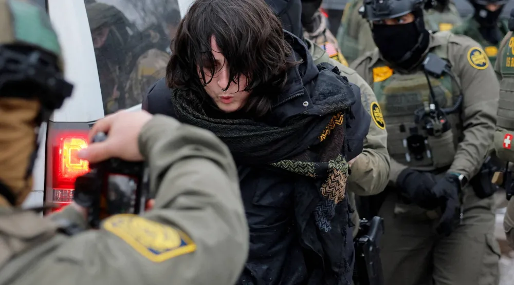 عناصر من بينهم شخص يحمل كاميرا يحتجزون متظاهرة في اليوم التالي لإطلاق النار المميت على رينيه نيكول غود من قبل أحد عناصر إدارة الهجرة والجمارك في مينيابوليس (رويترز)