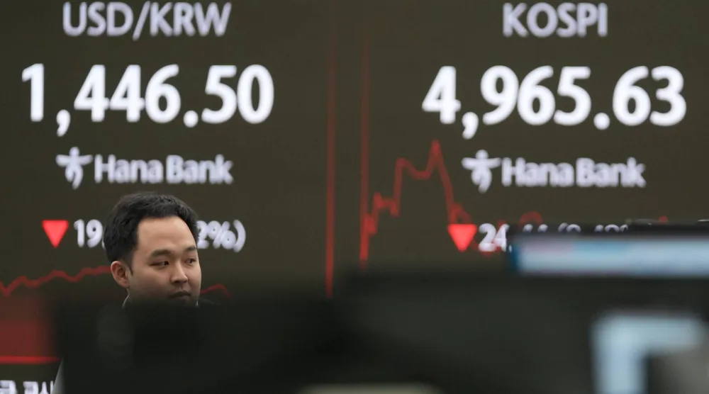 متداول يمرّ قرب شاشات تعرض مؤشر كوسبي وسعر صرف الدولار مقابل الوون في قاعة تداول بنك هانا بسيول (أ.ب)