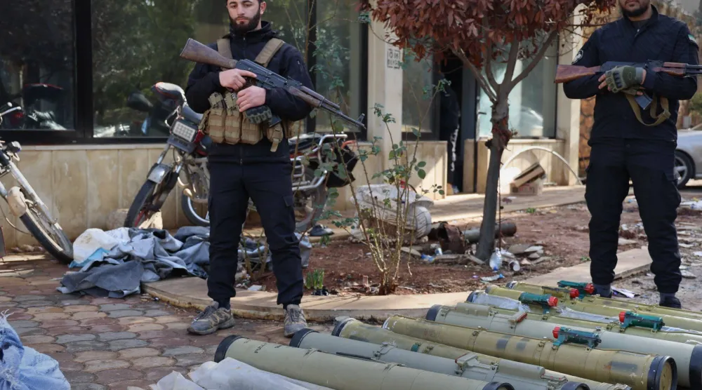 عنصرين من قوى الأمن السورية يقفان بجوار شحنة أسلحة كانت معدة للتهريب إلى لبنان (سانا)  