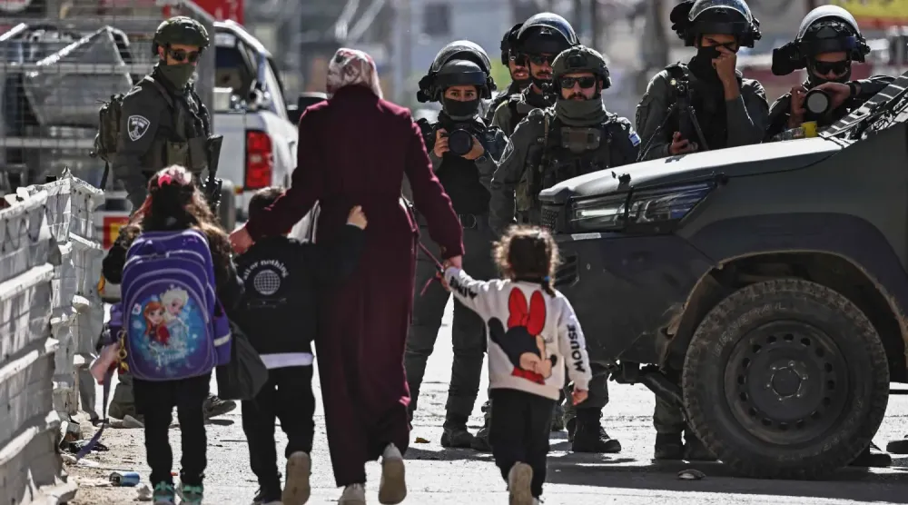 Dün Ramallah yakınlarındaki Kafr Aqab'da bir anne ve çocukları İsrail devriyesine doğru yürüyor (AFP).