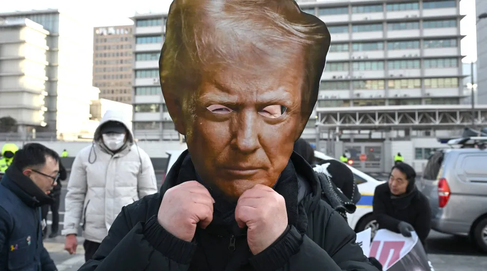 متظاهر يرتدي قناعاً لترمب خلال مسيرة احتجاجية لرفع الرسوم على كوريا الجنوبية أمام السفارة الأميركية في سيول (أ.ف.ب)