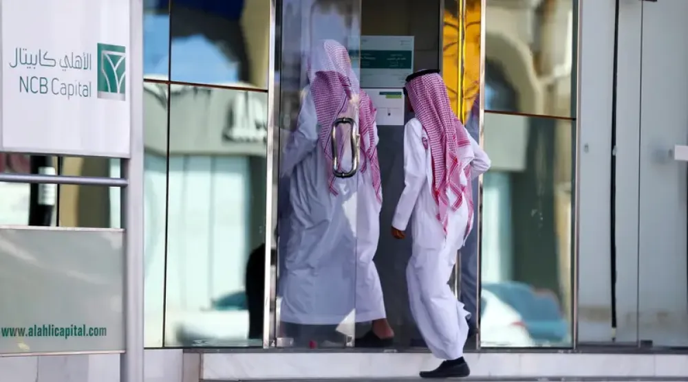 أفراد يدخلون أحد فروع «البنك الأهلي» في السعودية (رويترز)