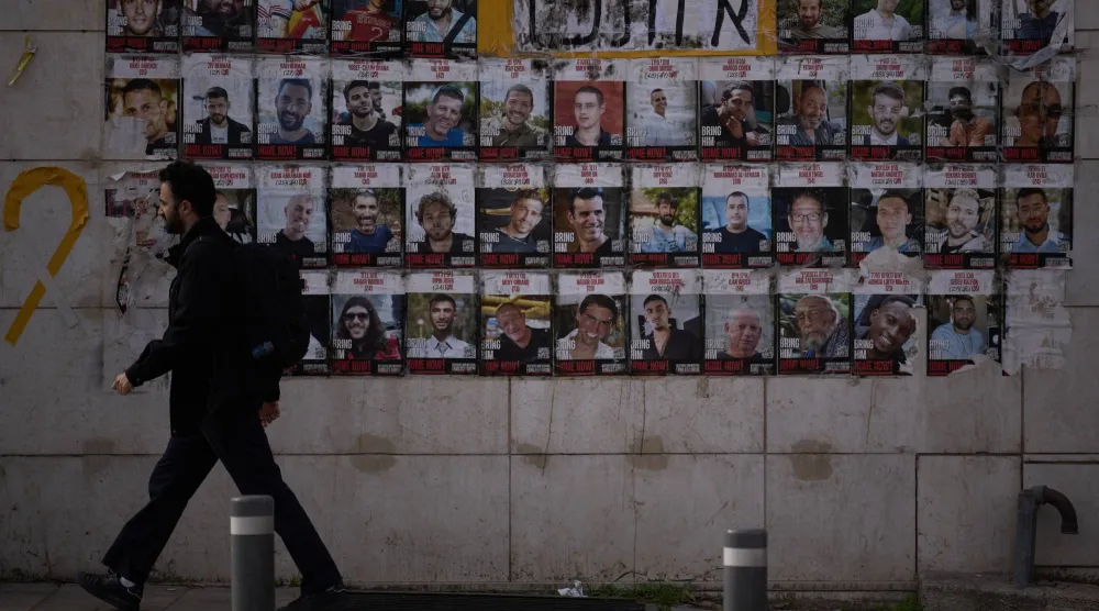 رجل يمر أمام صور لرهائن اختطفتهم حركة «حماس» معروضة في أحد شوارع القدس (أ.ب)