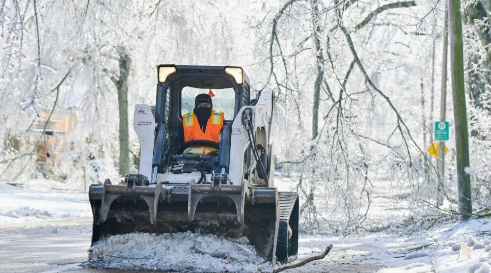 عامل يزيل الجليد من أحد الشوارع في أوكسفورد بميسيسيبي الأميركية (أ.ب)
