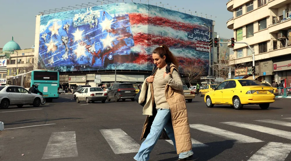 إيرانية تعبر ساحة «انقلاب» وسط طهران بالقرب من لافتة ضخمة مناهضة للولايات المتحدة (إ.ب.أ)