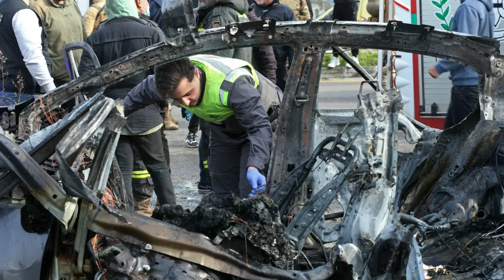 متطوع في الدفاع المدني يتفقد ركام سيارة استهدفتها غارة إسرائيلية بمنطقة الزهراني جنوب لبنان (أ.ف.ب)