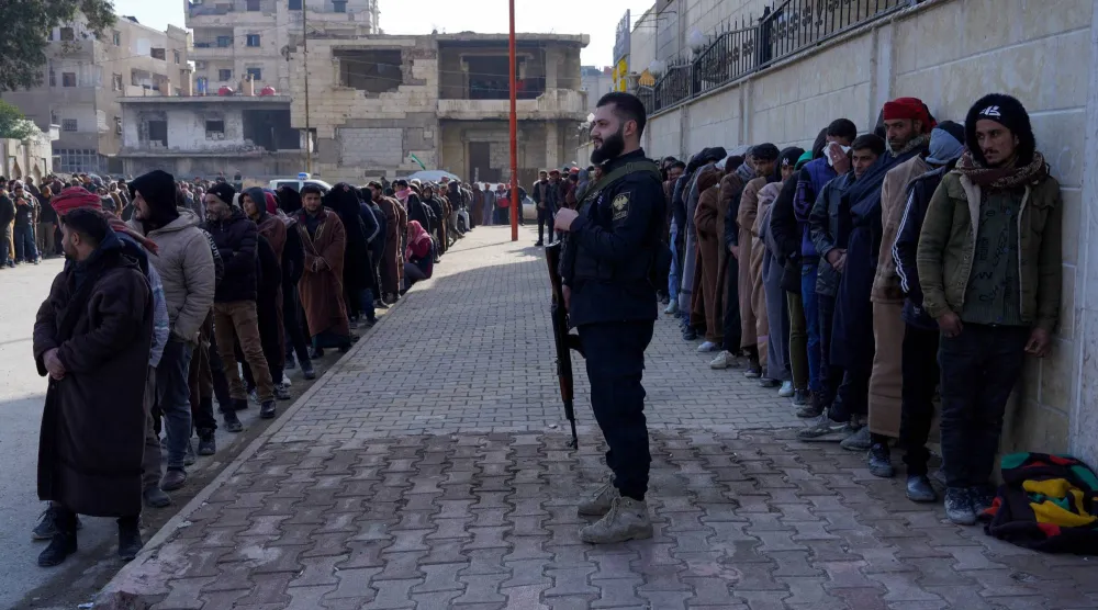 أفراد من قوات سوريا الديمقراطية (قسد) التي يقودها الأكراد يصطفون لتسوية أوضاعهم مع الحكومة السورية في الرقة (رويترز)