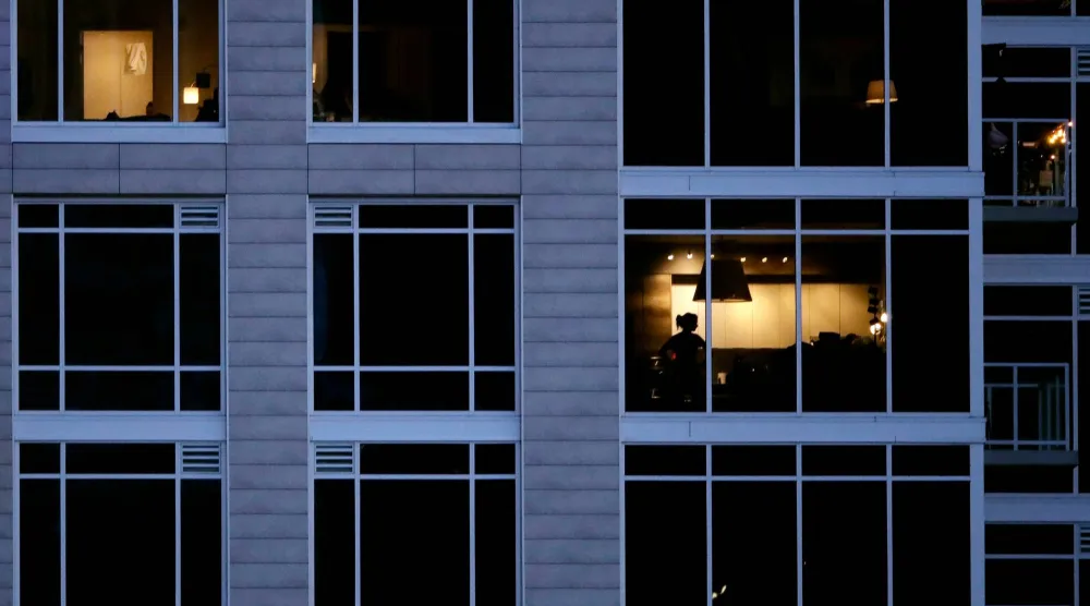 شخص ينظر من شقته في مبنى بمدينة كنساس بالولايات المتحدة (أ.ب)