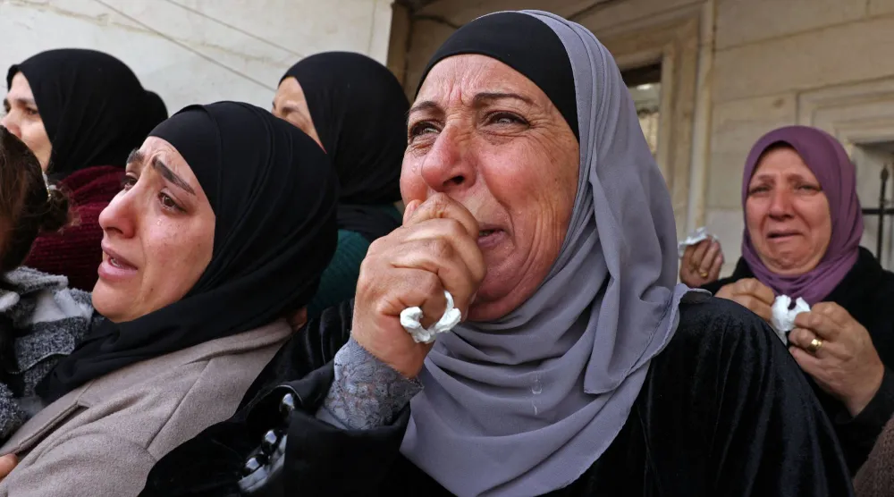 فلسطينيات يبكين الأربعاء خلال جنازة شاب قتلته قوة إسرائيلية في قرية الظاهرة على مشارف مدينة الخليل بالضفة الغربية المحتلة (أ.ف.ب)