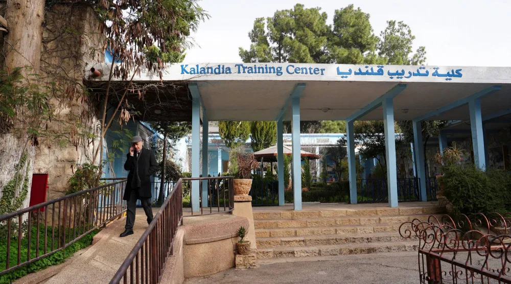 بهاء عوض مدير مركز تدريب «الأونروا» في قلنديا يتحدث عبر الهاتف أمام المركز بعد أن أفاد الموظفون بأن إسرائيل قطعت التيار الكهربائي عن المنشأة بالقرب من رام الله في الضفة (رويترز)