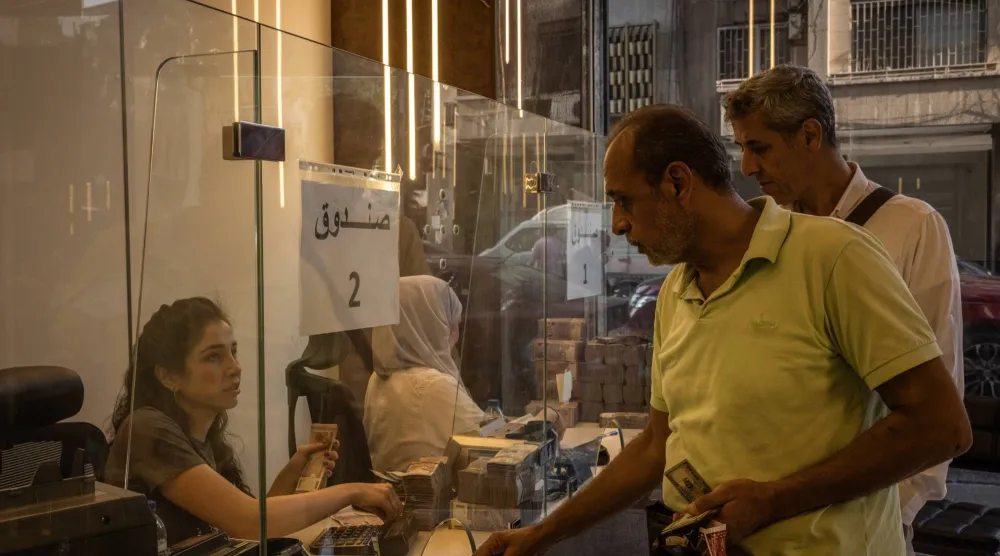 سيدة سورية تعمل بمحل صرافة في دمشق (غيتي)