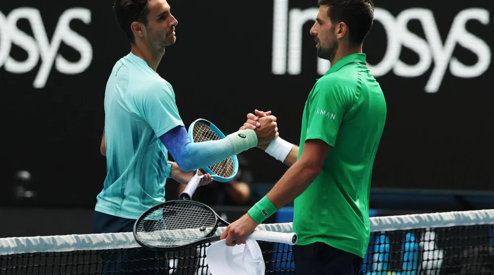 ديوكوفيتش (يمين) يواسي موزيتي الذي انسحب للإصابة وهو متقدم بمجموعتين (رويترز)