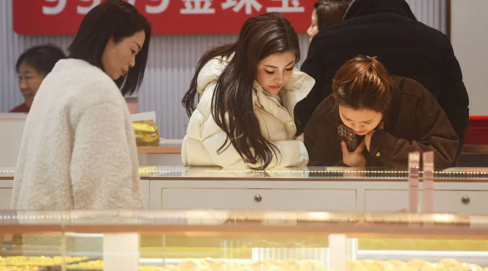 زبائن يتأملون مجوهرات الذهب في متجر للذهب بمدينة هانغتشو، شرق الصين (أ.ف.ب)