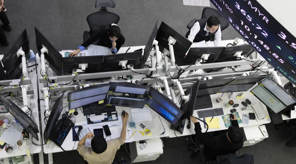 متعاملون كوريون جنوبيون يعملون أمام شاشات التداول في بنك هانا في سيول (إ.ب.أ)