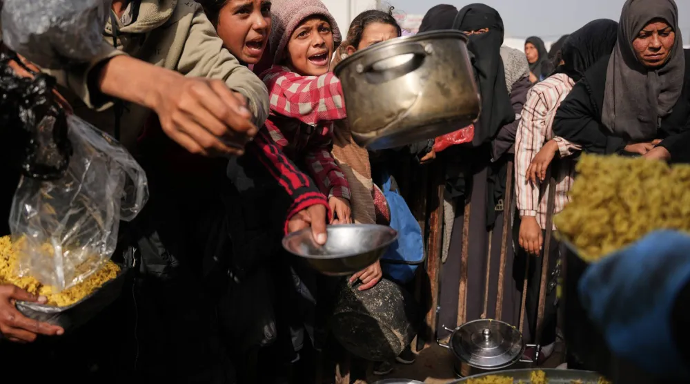 فلسطينيون ينتظرون الحصول على غذاء في خان يونس جنوب قطاع غزة 23 يناير الحالي (أ.ب)