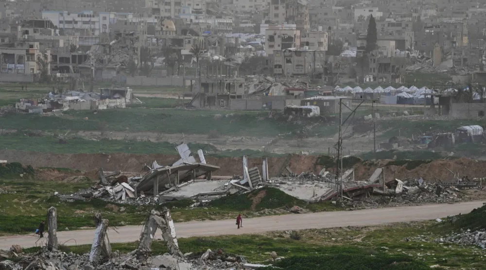 فلسطينيون يسيرون وسط الأنقاض التي خلفها القصف الإسرائيلي في الزهراء وسط قطاع غزة 28 يناير 2026 (أ.ب)
