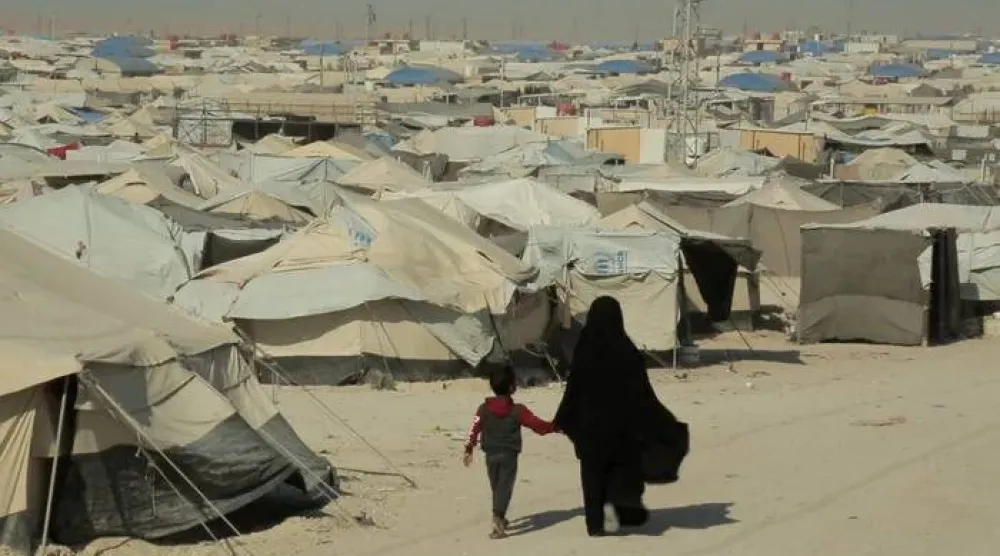 امرأة وطفل يسيران في «مخيم الهول» بسوريا (رويترز - أرشيفية)