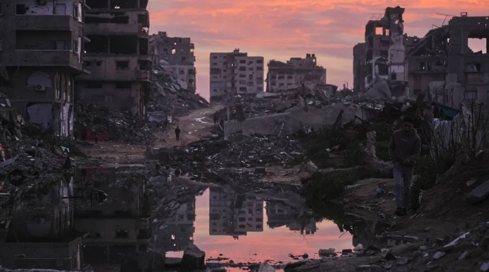 فلسطينيون يسيرون وسط مبانٍ دمرتها العمليات الجوية والبرية الإسرائيلية في مدينة غزة 29 يناير 2026 (أ.ب)
