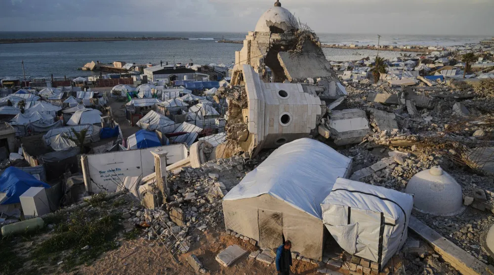 رجل يسير بين الخيام التي تؤوي فلسطينيين نازحين وسط الأنقاض التي خلفتها الغارات الإسرائيلية على مدينة غزة... 28 يناير 2026 (أ.ب)