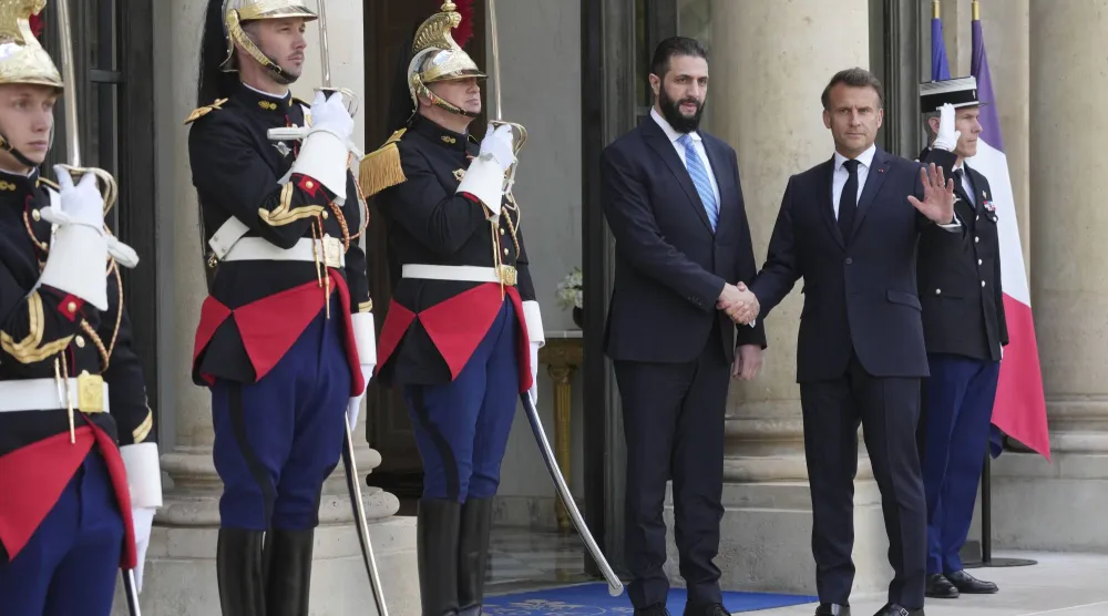 الرئيس الفرنسي إيمانويل ماكرون مستقبلاً الرئيس السوري أحمد الشرع على مدخل قصر الإليزيه في باريس مايو 2025 (أ.ب)