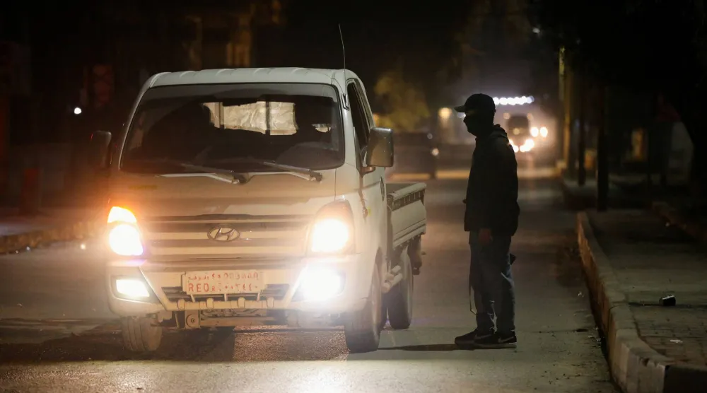 مسلح كردي يقف عند نقطة تفتيش في القامشلي (رويترز)