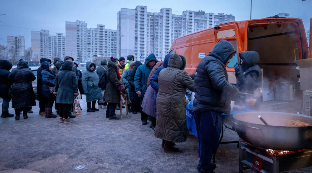 أوكرانيون يصطفون للحصول على وجبات طعام ساخن بعدما أدى قصف روسي إلى انقطاع الكهرباء عن مناطق واسعة في كييف (أ.ب)