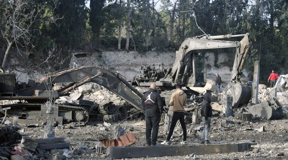 سكان يعاينون آليات لإعادة الإعمار متضررة جراء غارات إسرائيلية استهدفت معرضاً لها في منطقة الداوودية بجنوب لبنان (إ.ب.أ)