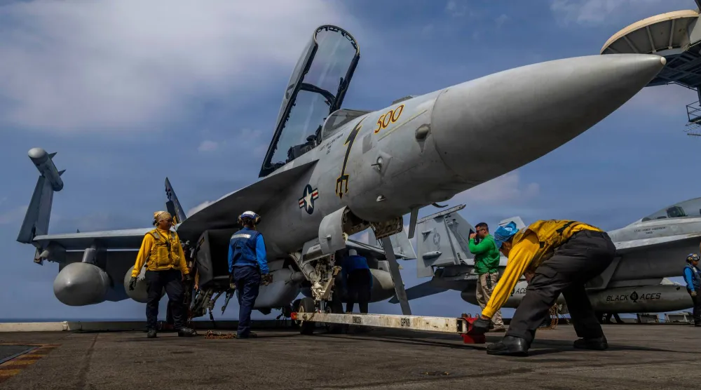 بحارة على متن حاملة الطائرات «لينكولن» يعدون في 21 يناير طائرة قتالية من طراز إيغل غرولر (أ.ب)