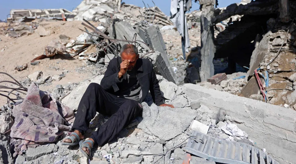 فلسطيني يجلس متأثراً فوق ركام مركز شرطة الشيخ رضوان في مدينة غزة بعد استهدافه بغارة إسرائيلية السبت (أ.ف.ب)