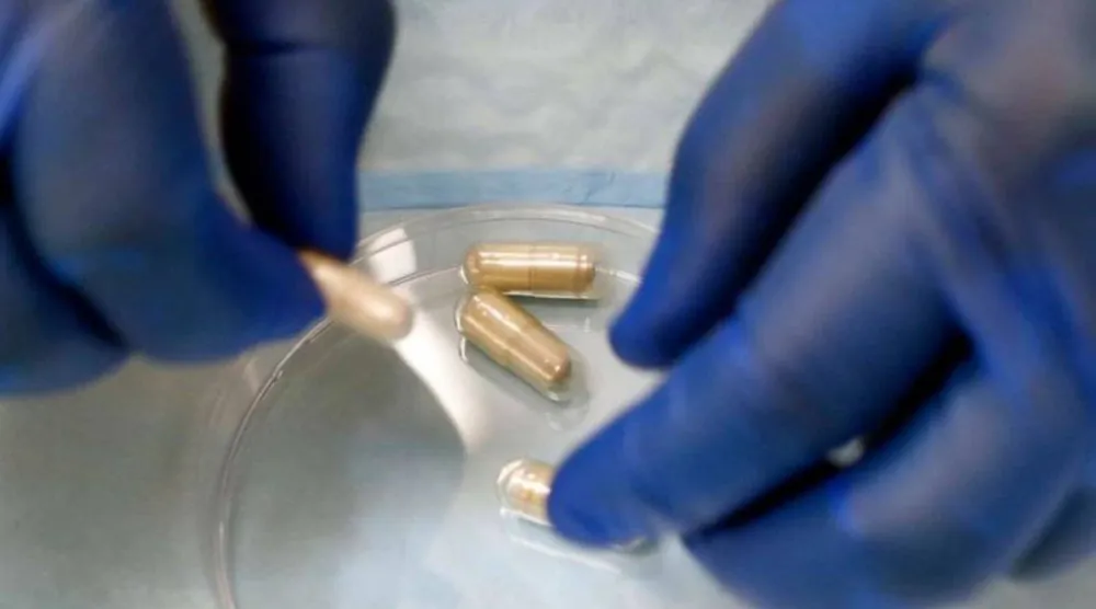 طبيب أمراض معدية يعد كبسولات دواء تحتوي على عينات براز في مختبر بكندا (أرشيفية - أ.ب)