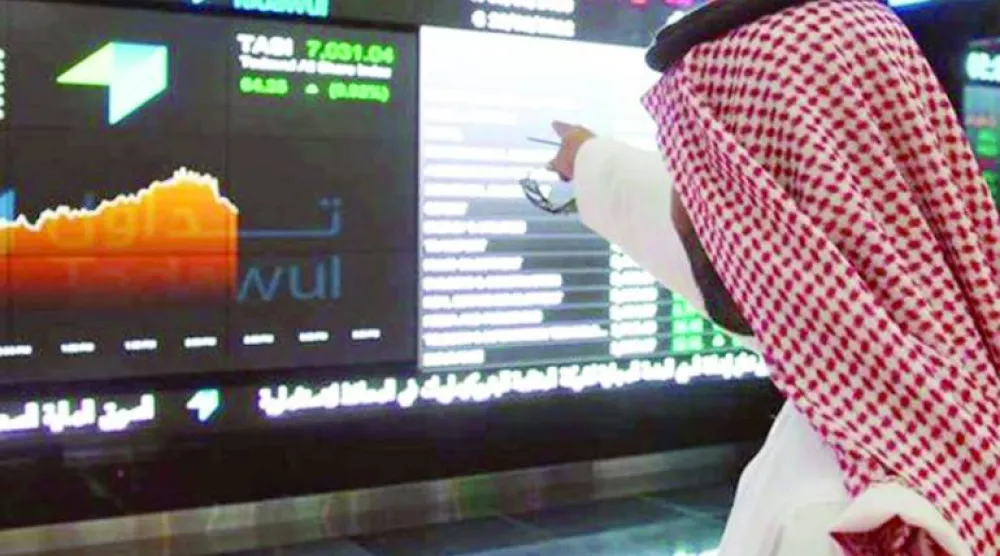 متداول يشير إلى تحرك الأسهم على شاشة في «السوق المالية السعودية» (رويترز)