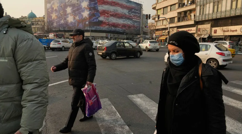 أشخاص يمرون أمام لوحة إعلانية في طهران تصور حاملة طائرات أميركية متضررة عليها طائرات مقاتلة معطلة ولافتة كُتب عليها بالفارسية والإنجليزية: «إذا زرعت الريح، فستحصد العاصفة» (أ.ب)