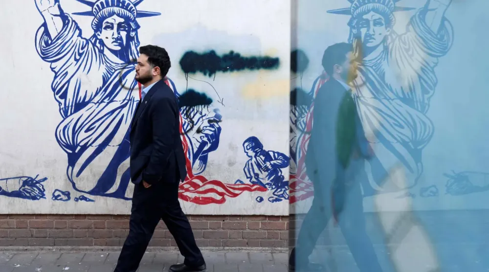 Yetkililerin ‘casus yuvası’ olarak adlandırdığı Tahran'daki ABD Büyükelçiliği’nin dış duvarlarında Özgürlük Heykeli'nin meşale tutan kolunun kırıldığını gösteren duvar resminin önünden geçen bir adam (AFP)
