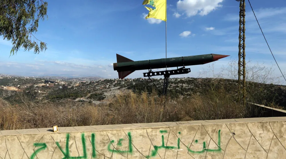 مجسّم لصاروخ رفعه «حزب الله» بمنطقة قلاويه في جنوب لبنان فوق شعار «لن نترك السلاح» (أرشيفية - إ.ب.أ)