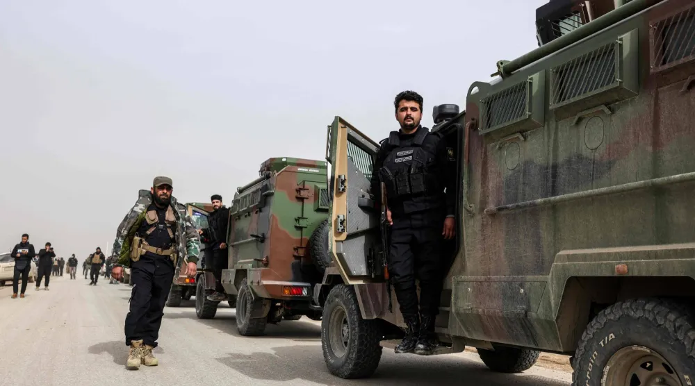 انتظار أفراد من القوات الحكومية السورية لبدء تحركاتهم على طريقٍ ريفيّ قرب مدينة الحسكة شمال شرقي سوريا صباح الاثنين (أ.ف.ب)